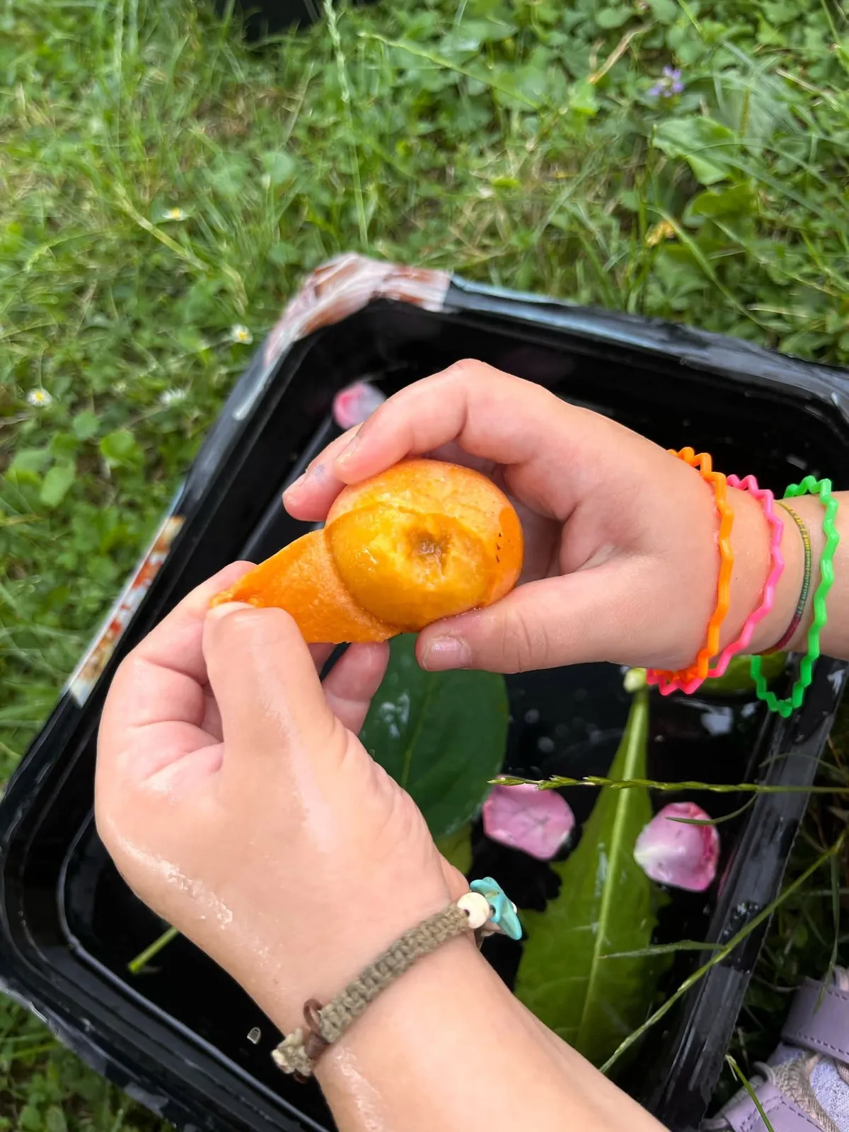 Mani di un bambino che sbuccia un frutto durante un'attività in giardino
