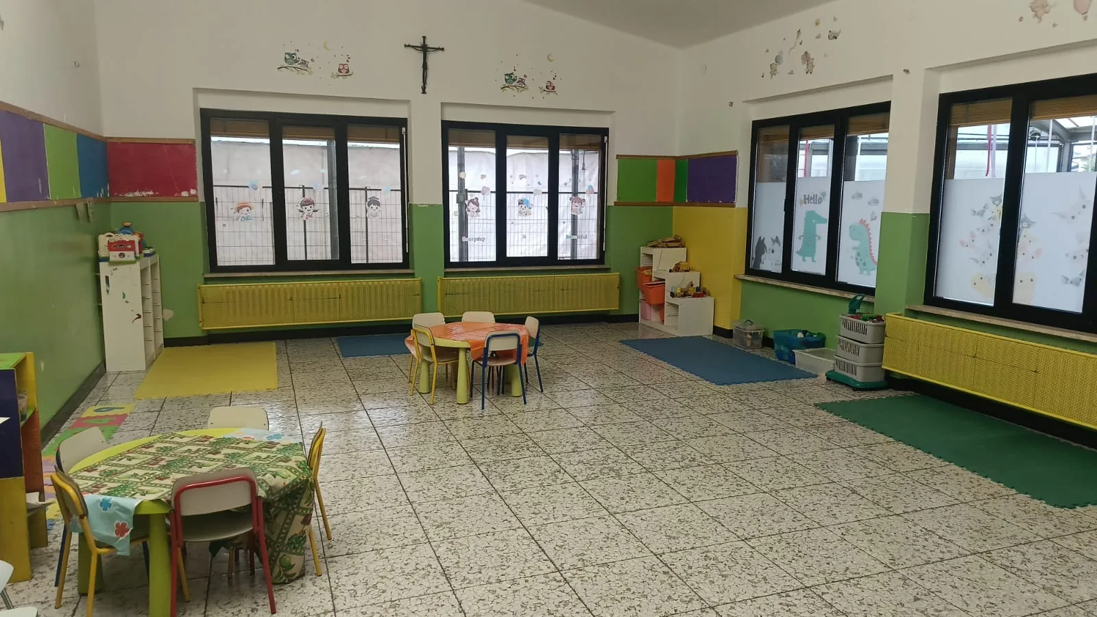 Aula luminosa della scuola dell'infanzia di Albegno con tavolini e angoli gioco