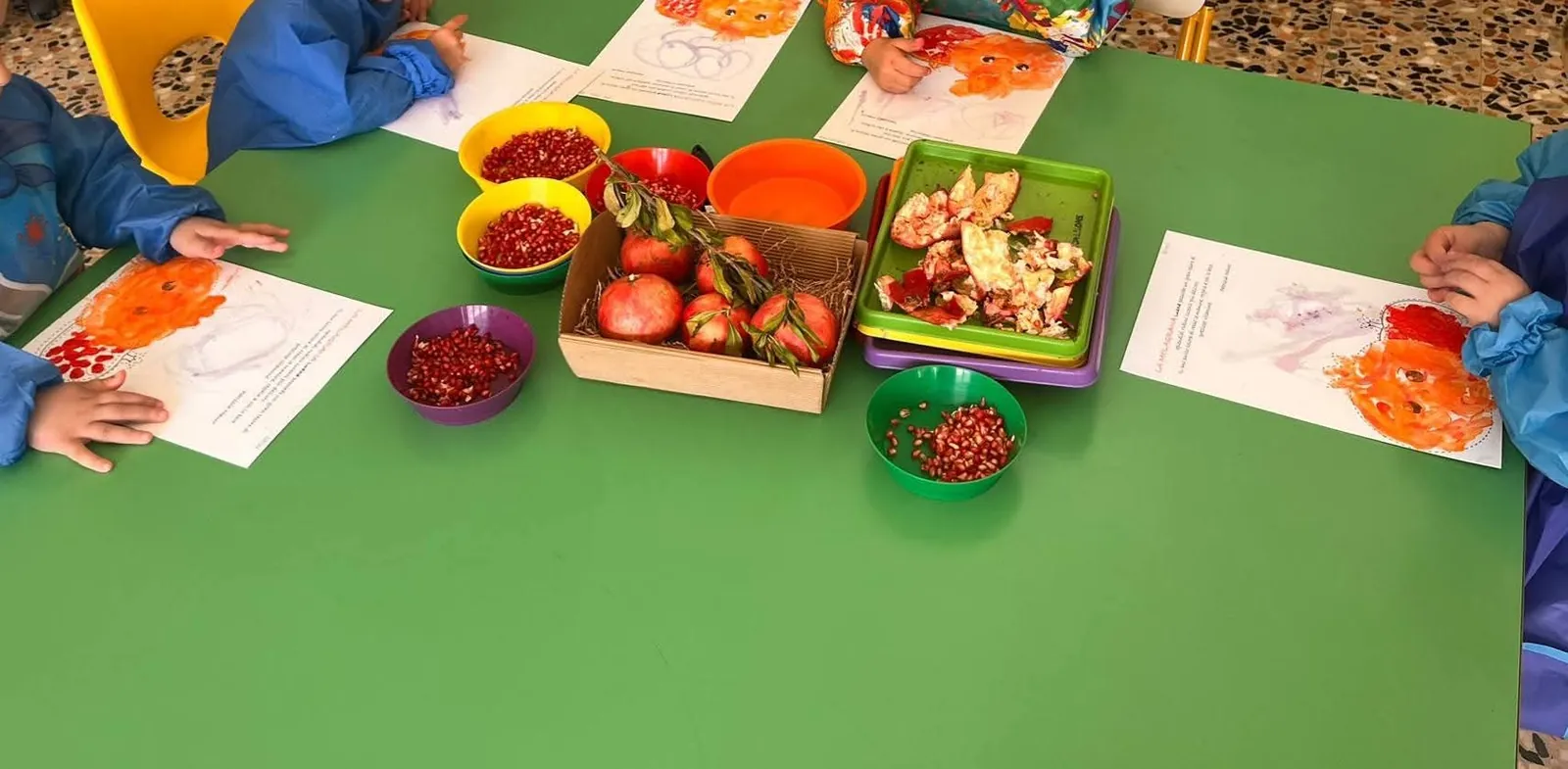 Bambini con il grembiulino dipingono con i chicchi di melagrana