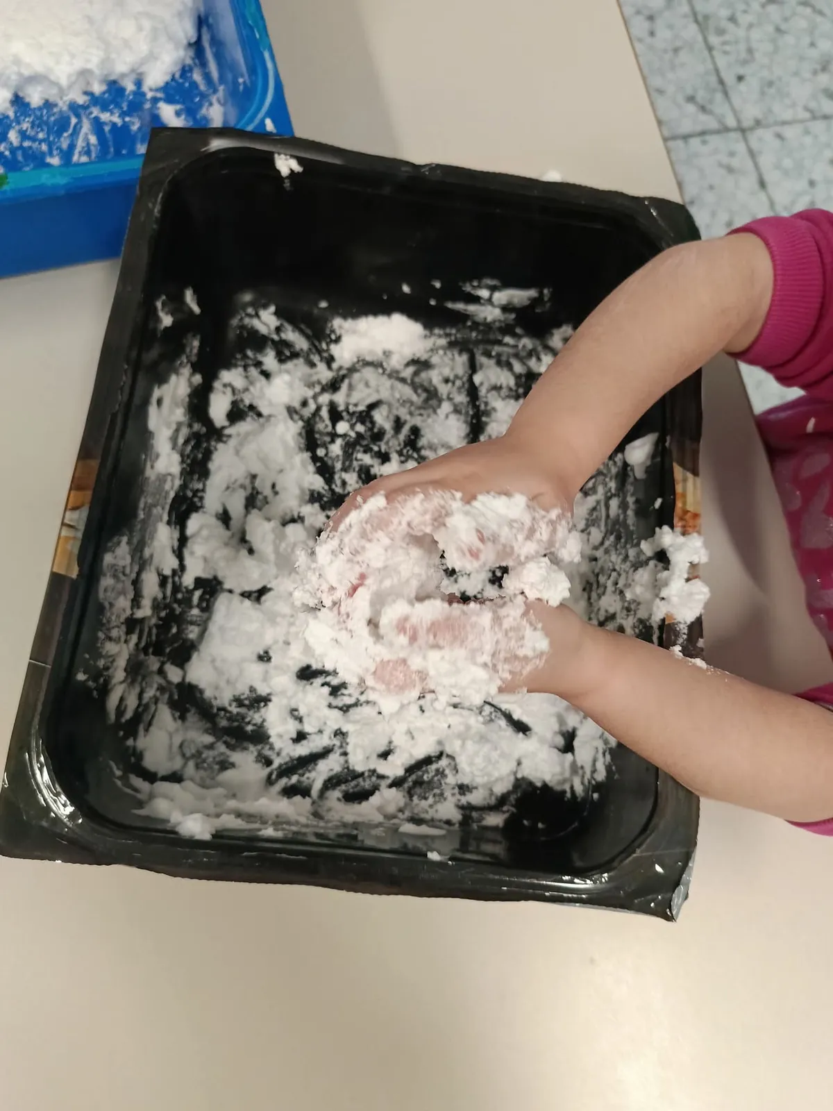 Mani di una bambina immerse nella schiuma durante il laboratorio di manipolazione