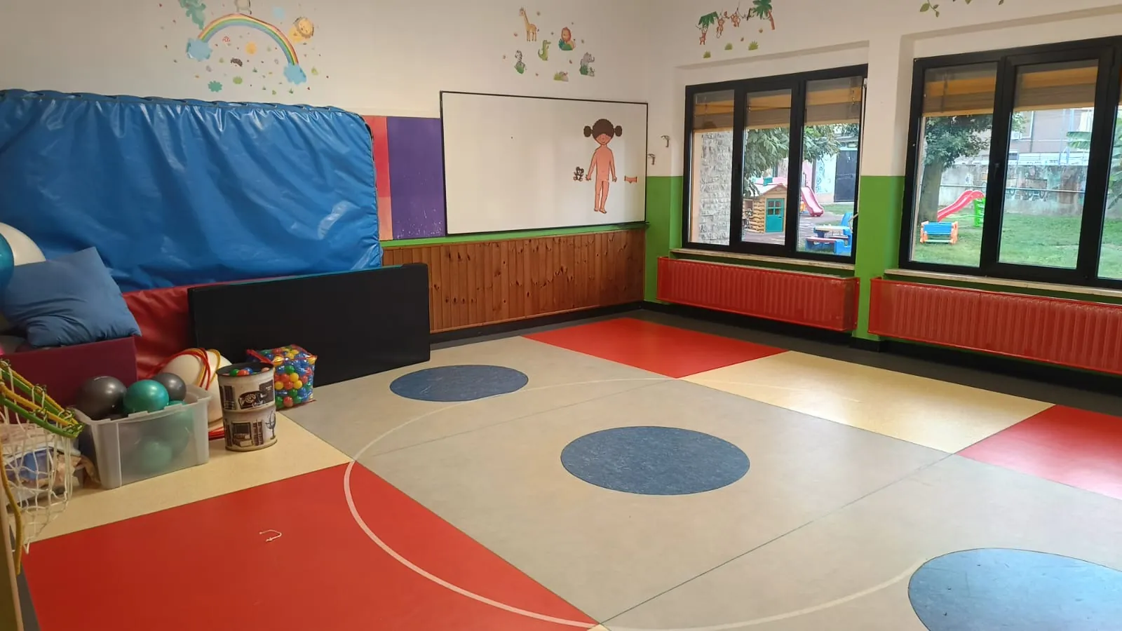 Sala per la psicomotricità con tappeti colorati e finestre sul giardino